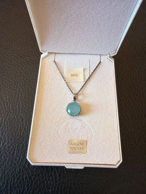 une boîte ouverte contenant un collier orné d'une pierre bleue