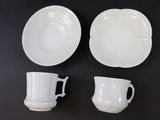 three white cups and saucers sitting on a black table