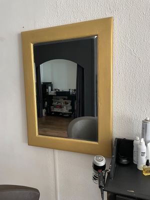 un miroir accroché au mur au-dessus d'un bureau, avec un sèche-cheveux et un sèche-cheveux