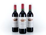three bottles of red wine sitting next to each other on a white surface