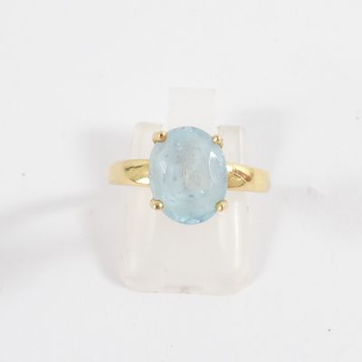 a close up of a gold ring with a blue topaz stone