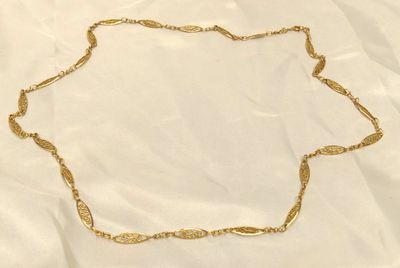 un gros plan d'un collier en or posé sur un tissu blanc