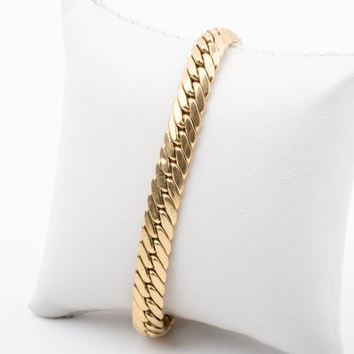 a close up of a gold bracelet on a white pillow