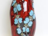 a red vase with blue flowers on it