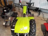 a green tractor parked in a garage next to other tractors