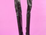 une paire de bottes en cuir noir sur fond rose
