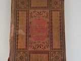 an old book on a white surface with a red cover