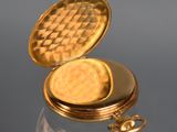a gold pocket watch sitting on a reflective surface