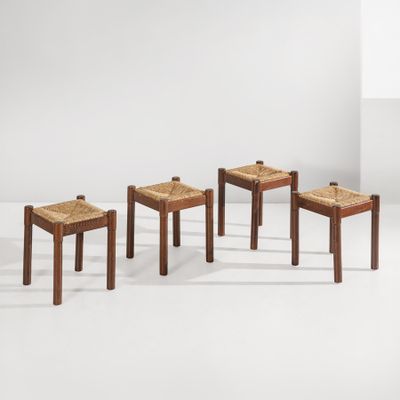 un ensemble de quatre tabourets en bois avec des assises en rotin dans une pièce blanche