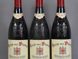 three bottles of red wine sit on a glass table