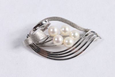 une broche en argent ornée de perles, posée sur un fond blanc