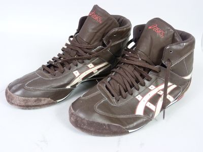 une paire de baskets marron et blanches avec des touches de rouge sur un fond blanc