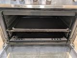 an open oven with a metal door and a black pan inside of it
