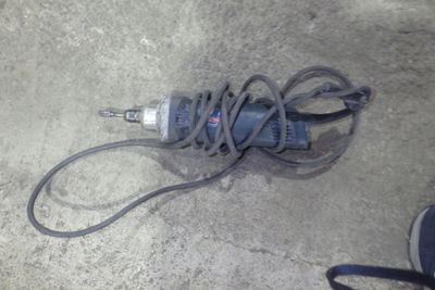 un câble relié à une perceuse posée au sol