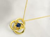 un gros plan d'un collier en or orné d'une pierre bleue au centre