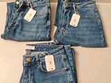 trois paires de jeans, encore étiquetées, posées sur une table