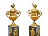 deux vases dorés posés sur une table en marbre, sur fond blanc