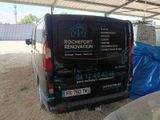 a van that is parked under a roof in the dirt