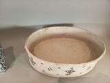 a white bowl sitting on top of a table next to a blue and white vase