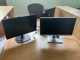two computer monitors sitting on a desk in an office