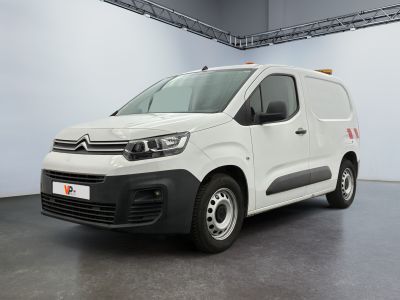 La camionnette blanche est garée dans une grande pièce au sol noir.