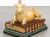 a statue of a sheep laying on top of a book