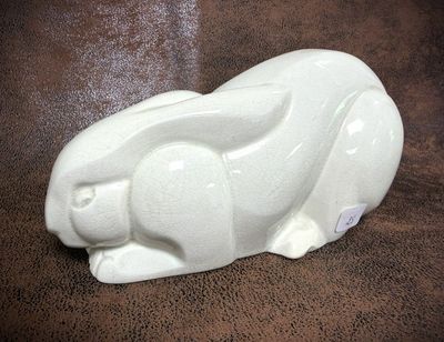 a white rabbit figurine sitting on a brown surface