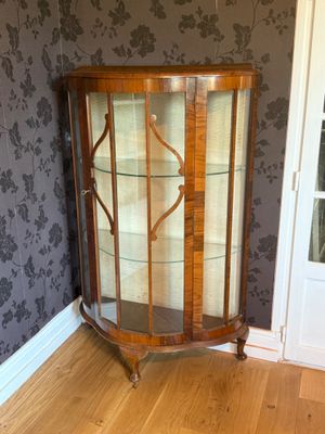 a glass display cabinet in the corner of a room