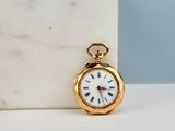 a small gold pocket watch sitting on a marble block