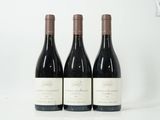 trois bouteilles de vin rouge sont alignées sur une surface blanche