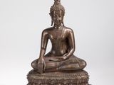 une statue en bronze représentant un Bouddha assis sur un rocher