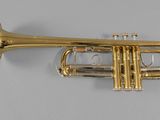 a gold trumpet sitting on top of a white surface