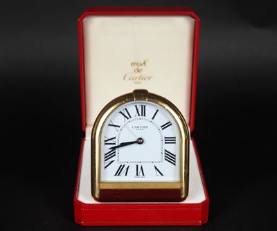 une petite horloge dans une boîte rouge posée sur une surface noire