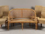 three wicker chairs and a bench in a room with a gray wall