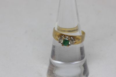 a gold ring with a green stone on top of a clear glass