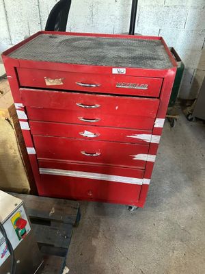 une commode rouge dans un garage, à côté d'une machine