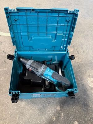 une boîte à outils bleue contenant une perceuse, posée par terre