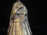 une cloche ancienne en laiton représentant une femme tenant un bébé dans ses bras