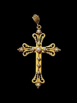 un pendentif en forme de croix en or orné de perles sur fond noir