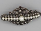 an antique silver and pearl broochle with pearls on a white background