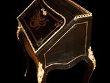 an antique writing desk with a black and gold decoration on the top