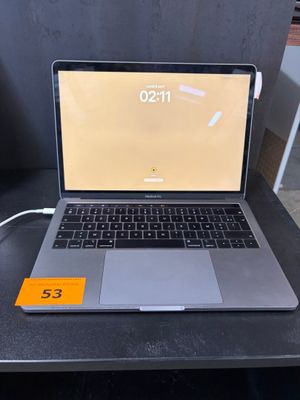un ordinateur portable ouvert posé sur un bureau, à côté d'un chargeur