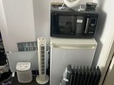 un micro-ondes, un réfrigérateur et un radiateur dans une petite pièce