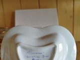 someone is holding a heart shaped plate with a note inside of it