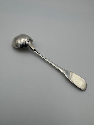 silver spoon with a spoon handle on a gray surface