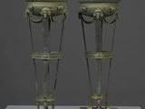 une paire de vases en bronze posés sur un socle blanc, sur fond gris