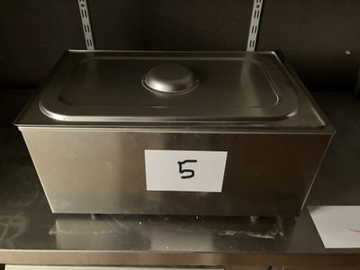 un récipient métallique portant un numéro, posé sur une étagère