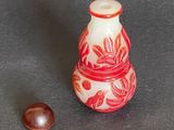 a small red and white vase next to a small brown object