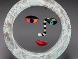 sculpture of a face in a circle with a black and white striped tie