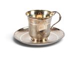 une tasse et une soucoupe anciennes en argent, posées sur une soucoupe, sur un fond blanc